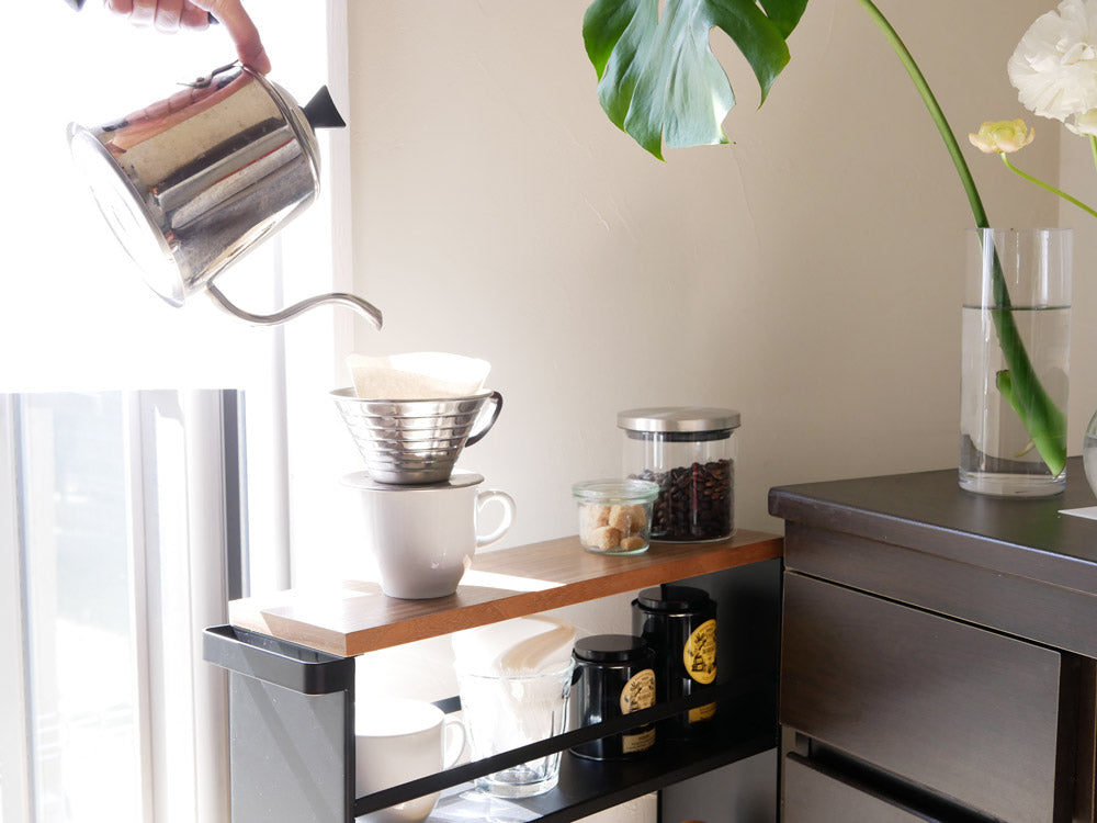 YAMAZAKIブランドのハンドル付きスリムワゴンがキッチンに配置され、テーブルウェアや花瓶、観葉植物が飾られている様子