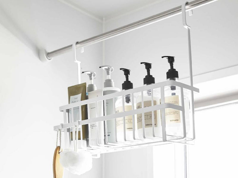 スチール製のタワー型引っ掛けバスルームバスケットが壁に掛けられ、周囲に棚やキッチン用品が配置されたバスルームの様子