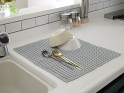 テイジンのあっちこっち水切りマットがキッチンの流し台の上に置かれ、食器や調理器具が周囲に配置された様子