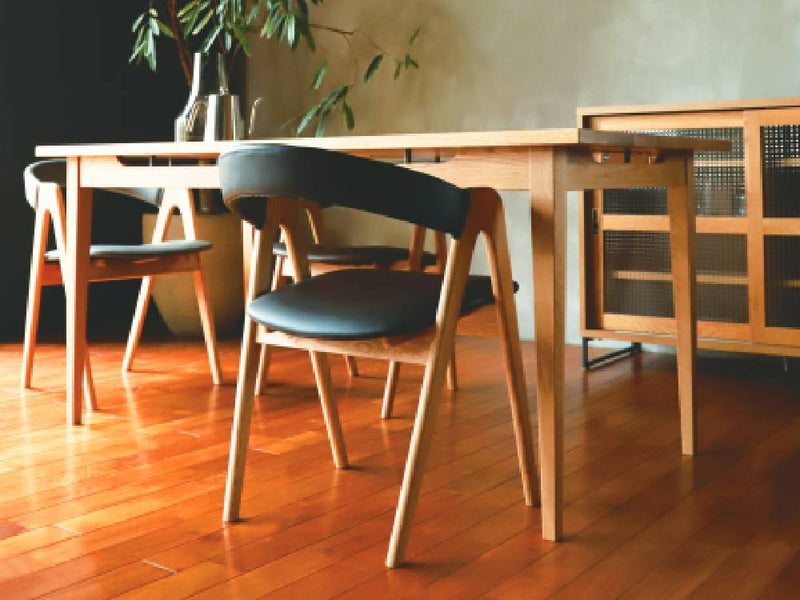 アデペシュのオーク製cobakホールドアームチェアが木製フローリングのリビングルームに配置されている様子