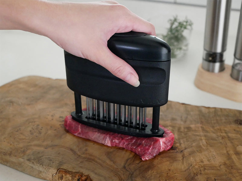 キッチン用品「ニクサスプロ」を使用してまな板上の肉を柔らかくしている様子