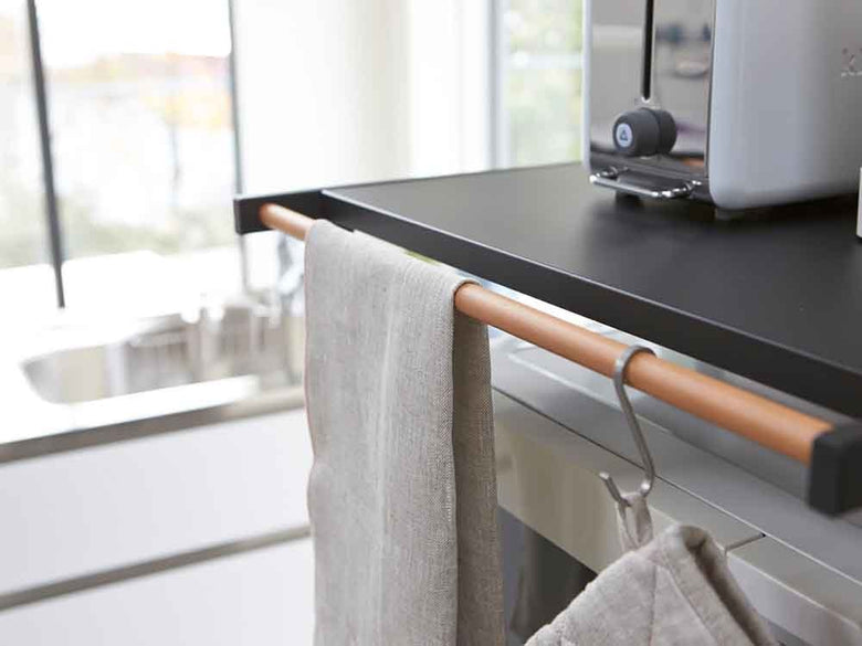 キッチンカウンター上に置かれたYAMAZAKIタワーのスチール製ゴミ箱上ラック。天然木のハンガーバーが備えられ、調理器具が整然と配置されています