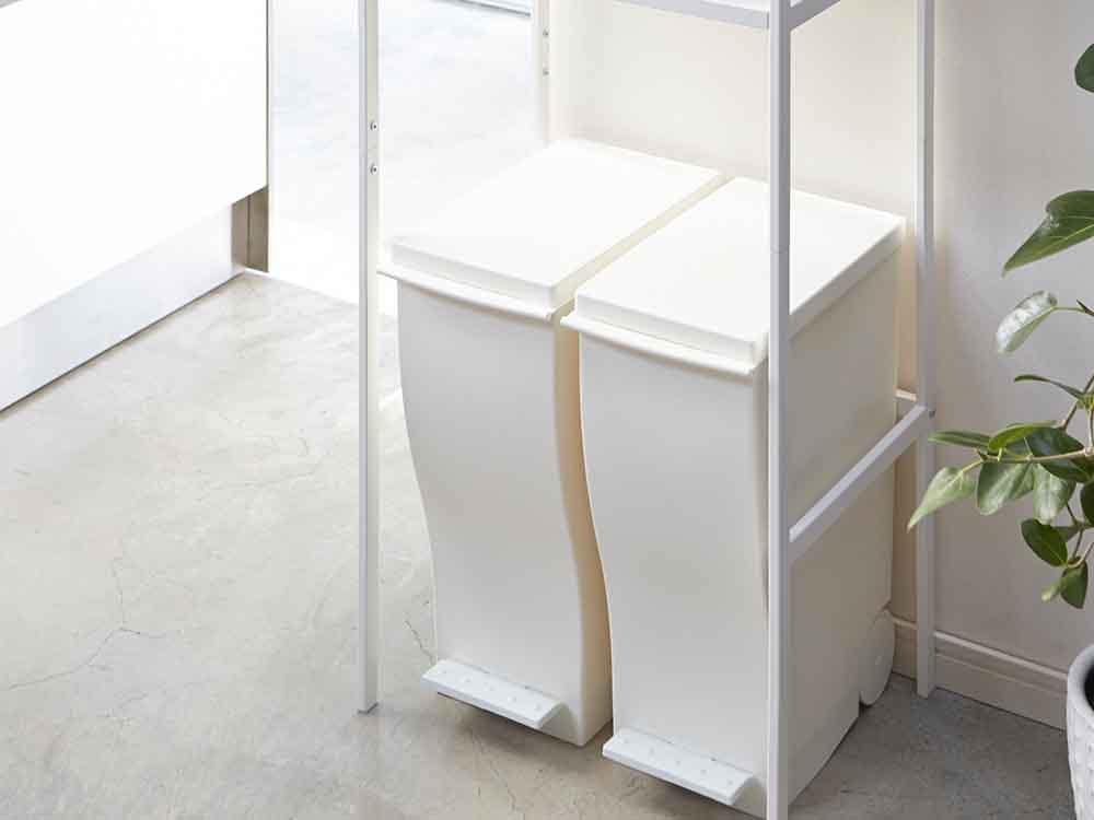 YAMAZAKI Towerブランドのゴミ箱上に設置されたスチール製棚と天然木ハンガーバーを備えた家庭用デザインラック