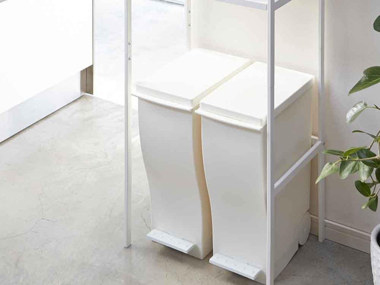 YAMAZAKI Towerブランドのゴミ箱上に設置されたスチール製棚と天然木ハンガーバーを備えた家庭用デザインラック