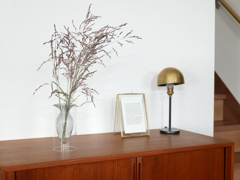 POSH LIVINGのガラス製フロートベースが木製の床のある居室に置かれ、花瓶やインテリア小物と共に飾られている様子