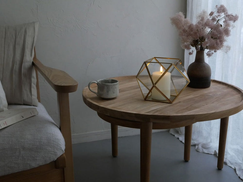 ホーンプリーズ製の真鍮フレームとガラスケースに収められたフィギュアが、木製のコーヒーテーブルと花束と共に配置されたディスプレイ