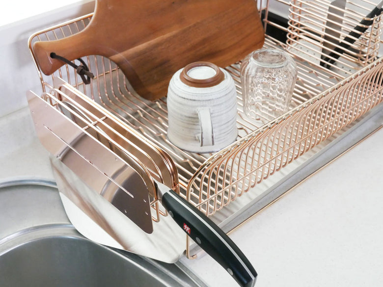 hanautaブランドのローズゴールドメッキステンレス製横置き水切りラック。カトラリーポケット付きでキッチンに設置された様子