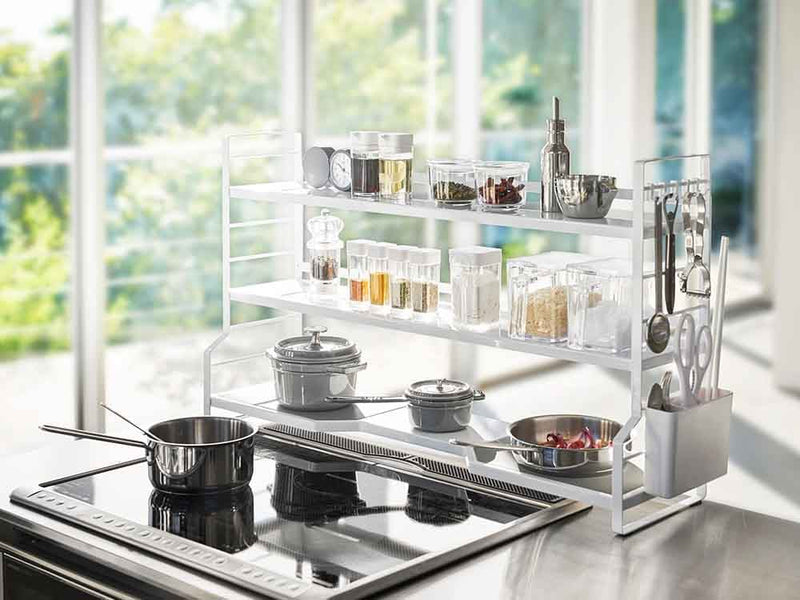 YAMAZAKI/towerのスチール製コンロ奥ラックがキッチンカウンター上に設置され、複数の棚とカトラリーポケットが見える収納具