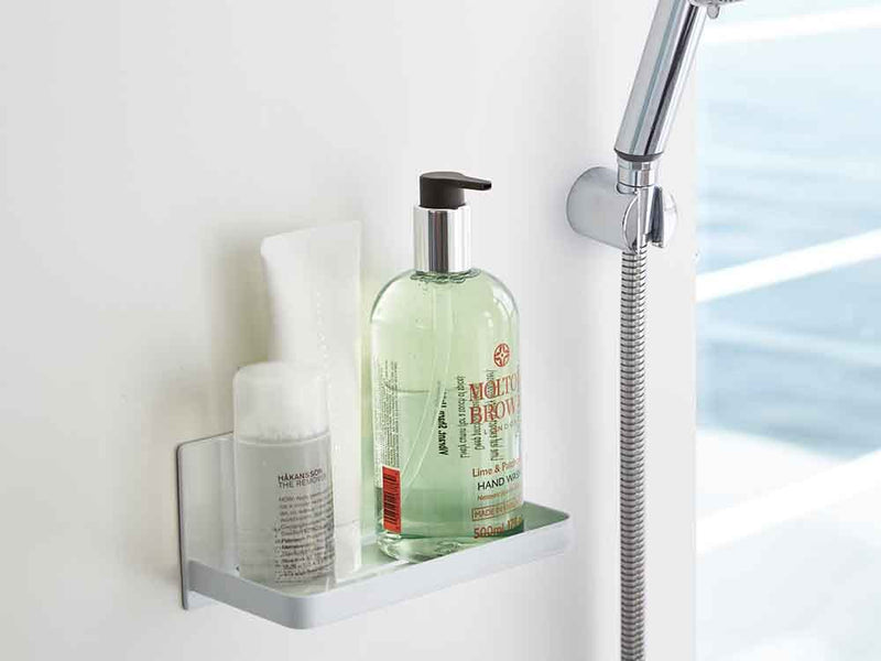 YAMAZAKI/towerのマグネットバスルームラックが浴室のスチール壁に設置され、ソープディスペンサーやボトルを収納している様子