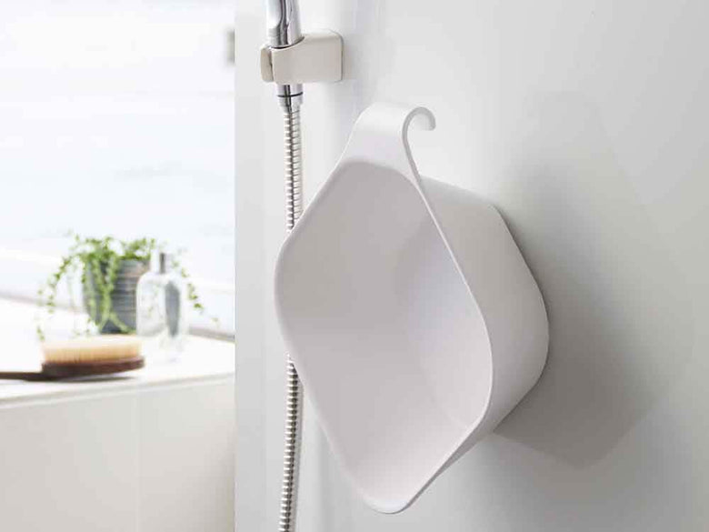 マグネットで壁に固定された浴室用湯おけ