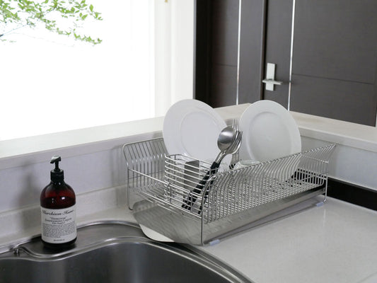 ハナウタ製ローズゴールドメッキのステンレス横置き水切りラックがキッチンカウンター上で食器やカトラリーを整理している様子