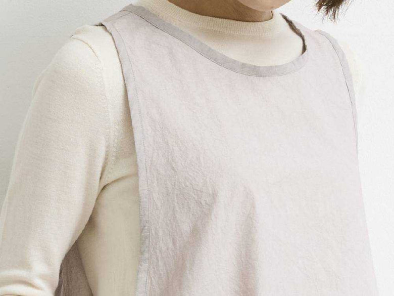 グレージュ色のビブエプロンを着用したモデル