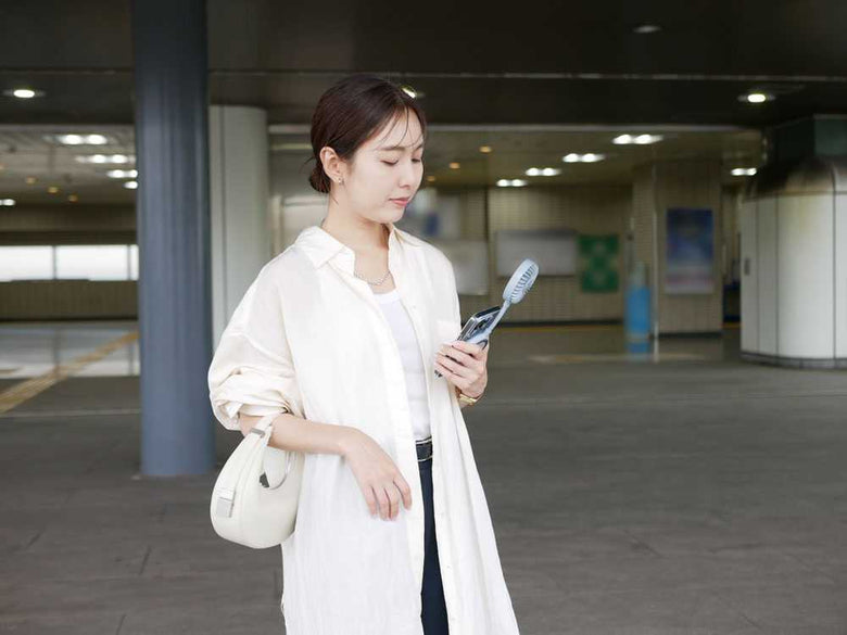 モデルがハンドバッグを持って笑顔でセーターを着用