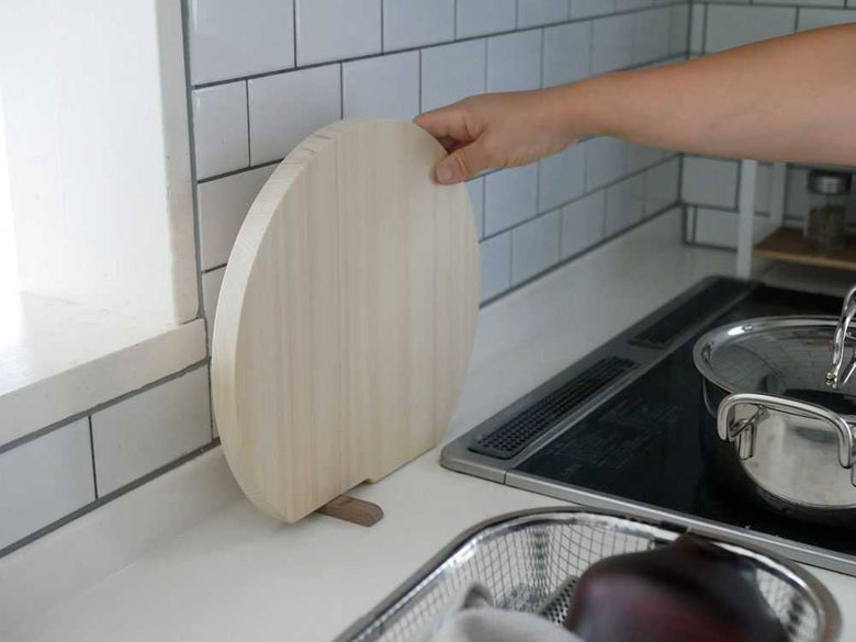 ヒノキの立つまるいまな板と木製調理器具が揃うキッチン