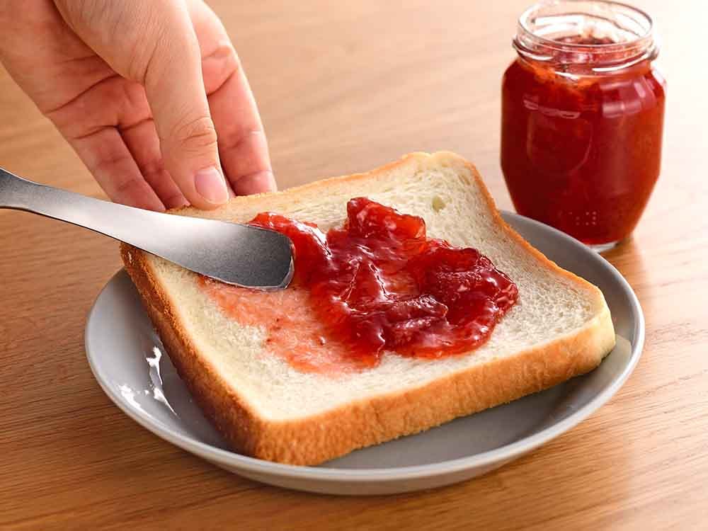 テーブルを汚さないジャムスプーンでパンにジャムを塗る