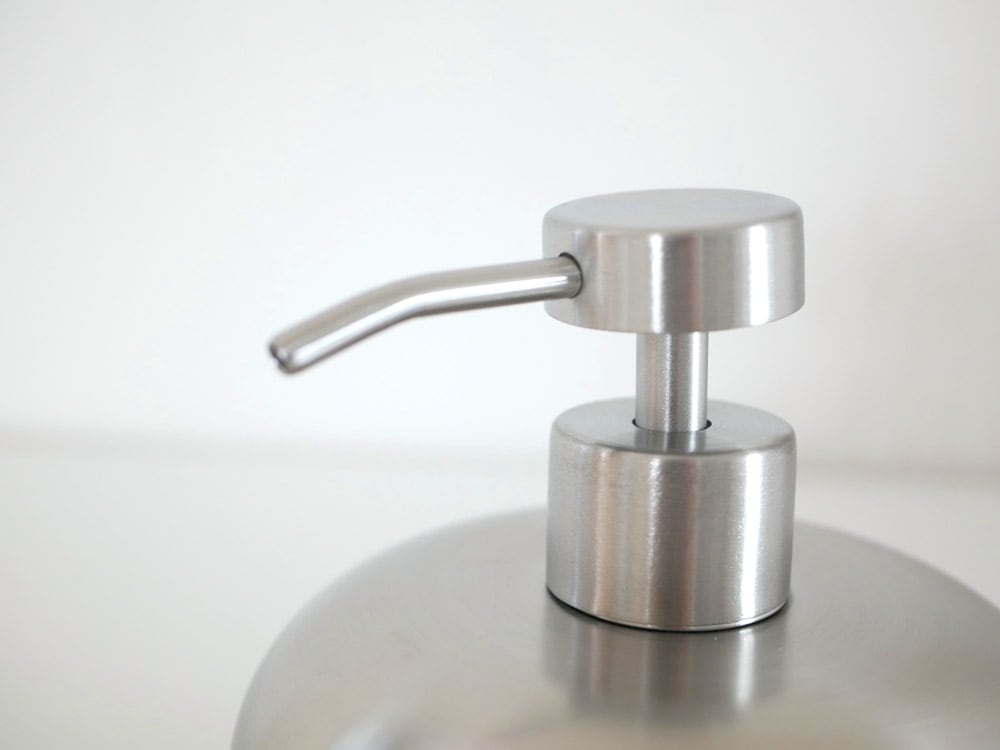 シルバーのステンレスソープディスペンサーと観葉植物、ランプ