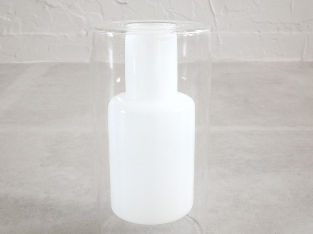 ポッシュリビングのガラス製フロートベースに円柱形のボトルが配置された静物写真