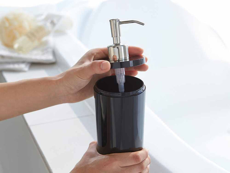 YAMAZAKI/toscaのツーウェイディスペンサーラウンドがバスルームの洗面台に設置されており、ABS樹脂製ボトルとステンレス製ポンプが組み合わさったソープディスペンサーの周りに観葉植物が配置されています