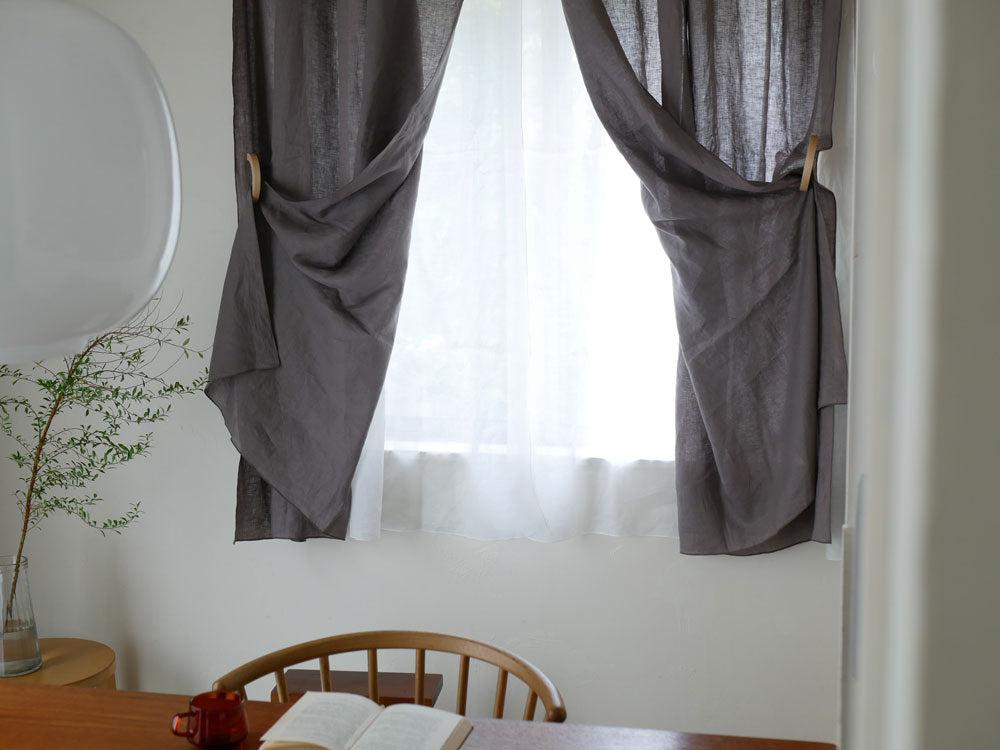 灰色カーテンに掛けられたウッドリングタッセル