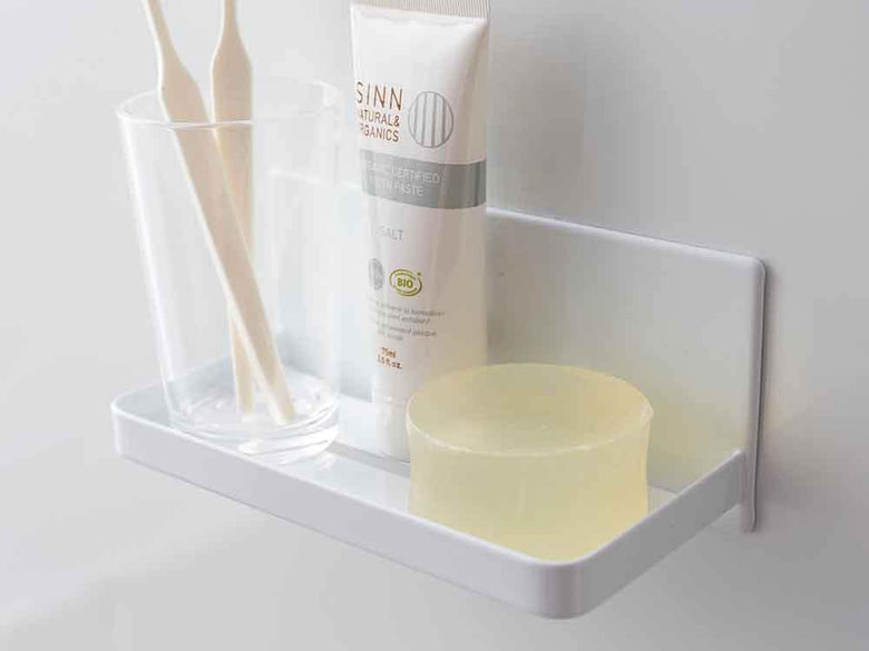 YAMAZAKI/towerのマグネットバスルームラックが浴室のスチール棚に設置され、プラスチック製ボトルやソープディスペンサーが整然と並んでいる様子