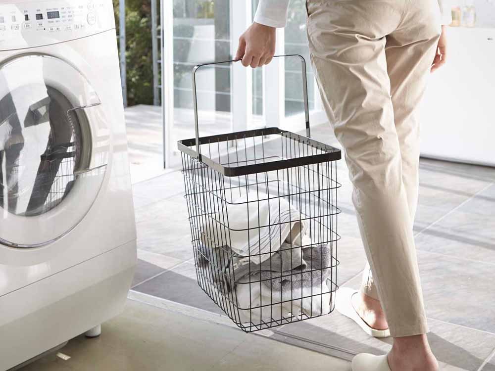 スチール製のランドリーワイヤーバスケットと洗濯機、乾燥機が配置された洗濯室の風景