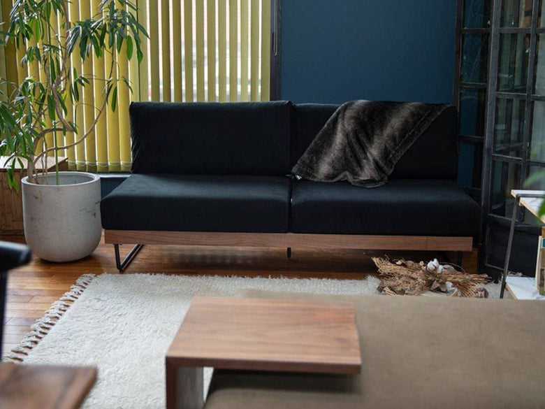 ナチュラル素材のソファとデイベッド、クッションと観葉植物が配置されたリビングルーム