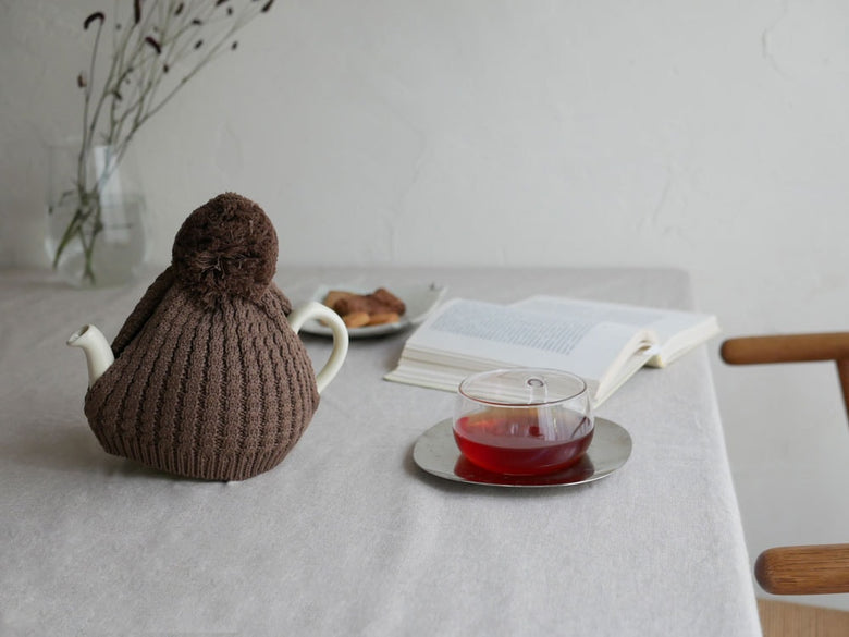 ロンドンポタリ製ウール編みオリジナルティーコージーがティーポットを包む