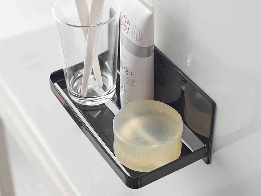 YAMAZAKIタワーのマグネットバスルームラックがスチール製の浴室壁に取り付けられ、ボトルやキッチン用品を整理している様子