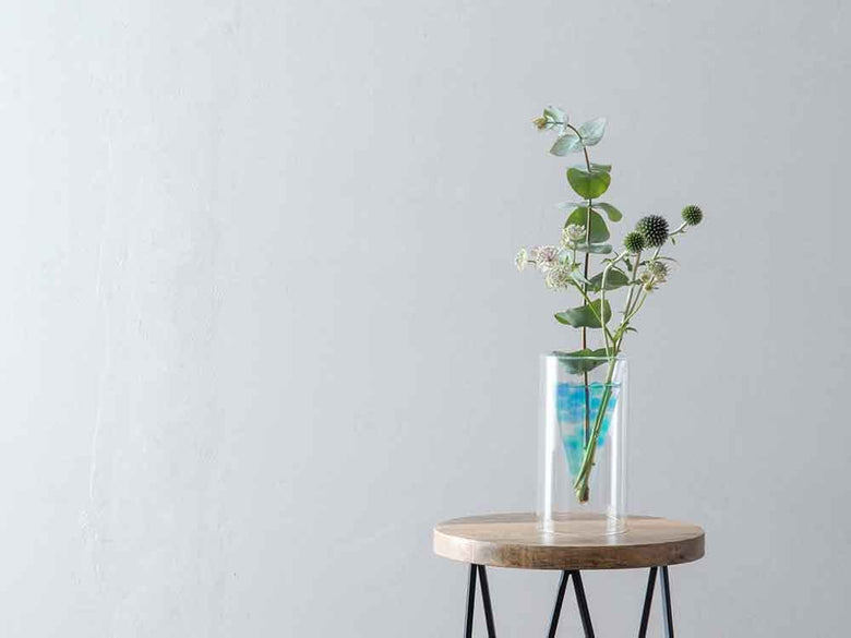 ポッシュリビング製ガラスフロートベースが木製プランク上に置かれた円柱形の花瓶と観葉植物