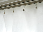 銀色のカーテンクリップが掛かったシャワーカーテン