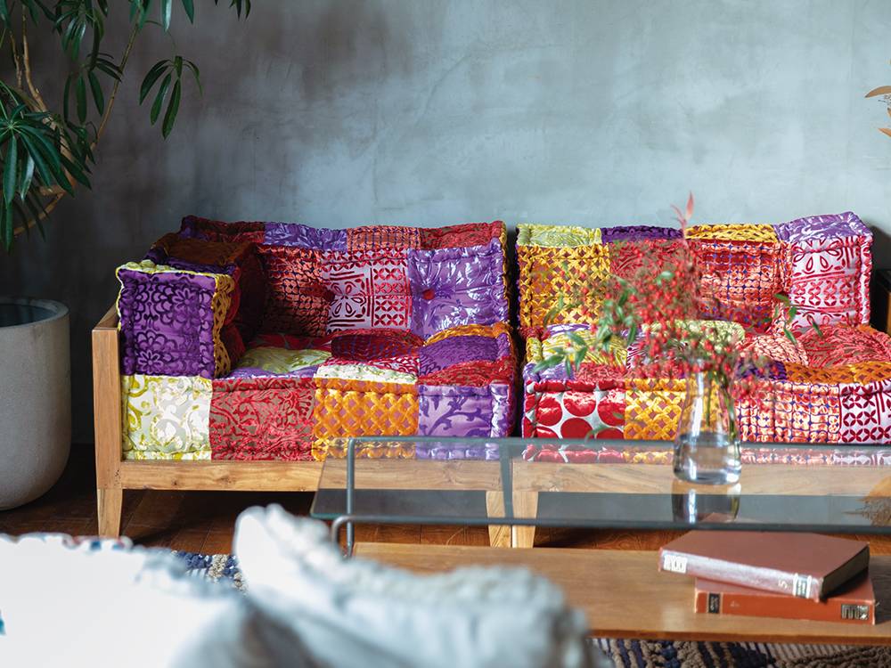 黄色とピンクのパッチワーククッションが配置されたリビング