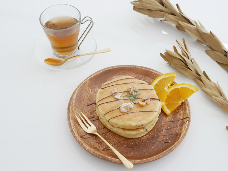 セイラスのエレガンテ18-10ステンレスゴールド製カトラリーセットが、パンケーキやフルーツと共に朝食テーブルに美しく並べられている様子