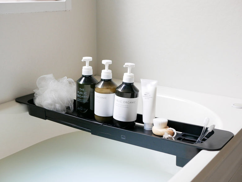 ヤマザキのタワー伸縮バスタブトレーが浴槽にセットされ、飲み物や読書用のアイテムが置かれている様子