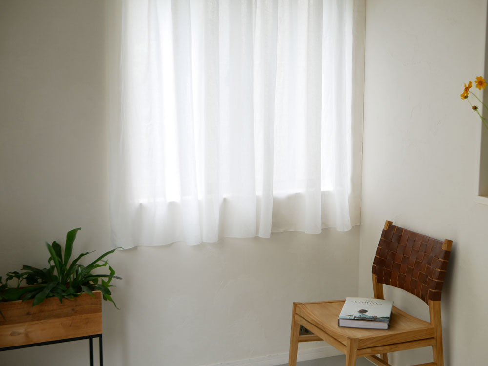 リネン100％のクリップ留めカーテンが窓に掛かっている様子。ナチュラルでシンプルなデザイン。