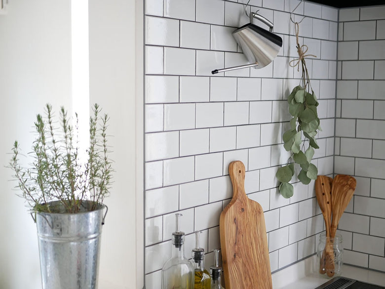 SALUSのステンレス製ミッテジョウロ。キッチンカウンターに置かれた大小2サイズで、花や果物と共に配置された静物写真。