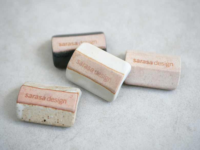 sarasa design×イブキクラフトの白色陶器製箸置きが他の小物とともにテーブル上に配置されている