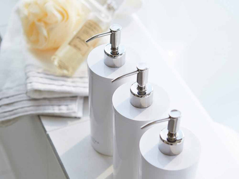 YAMAZAKI/toscaの白いツーウェイディスペンサー ラウンド、500ml容量のソープディスペンサーがバスルームのシンクに設置されている様子