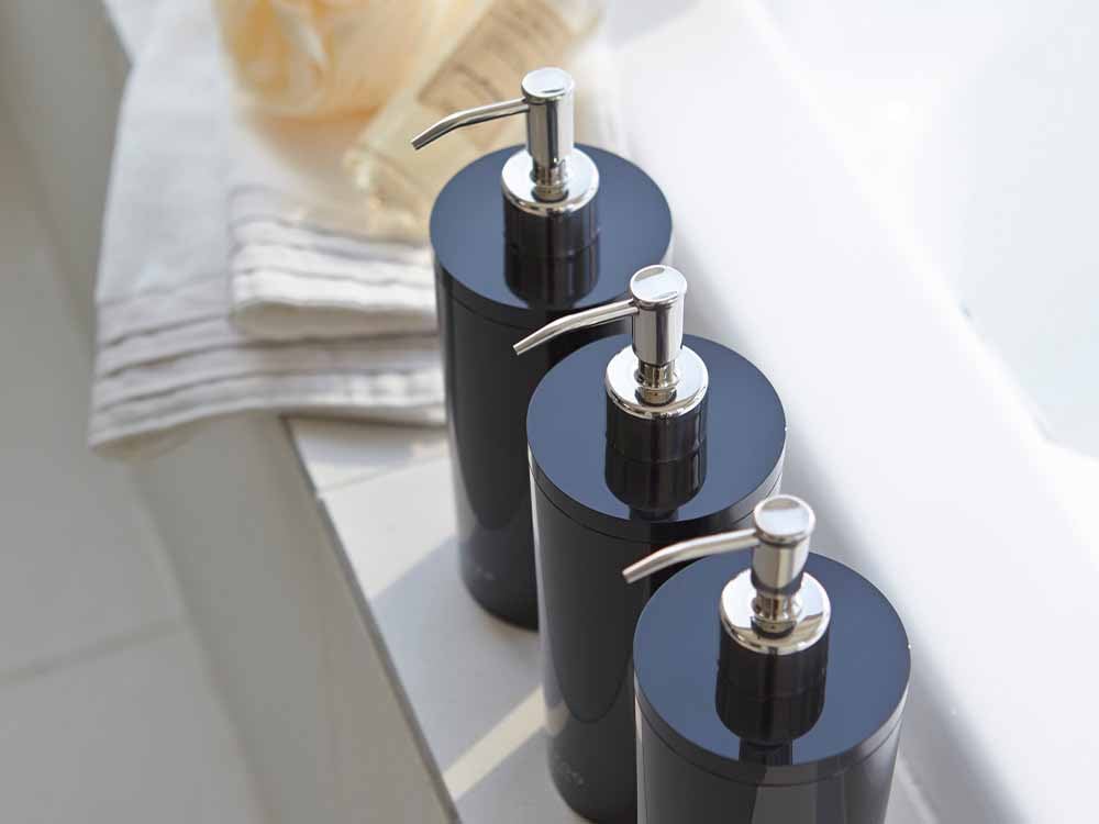 洗面所の陶器製シンクにYAMAZAKI/toscaのツーウェイディスペンサー ラウンドが設置され、タップやボトル、観葉植物と共に配置されている様子