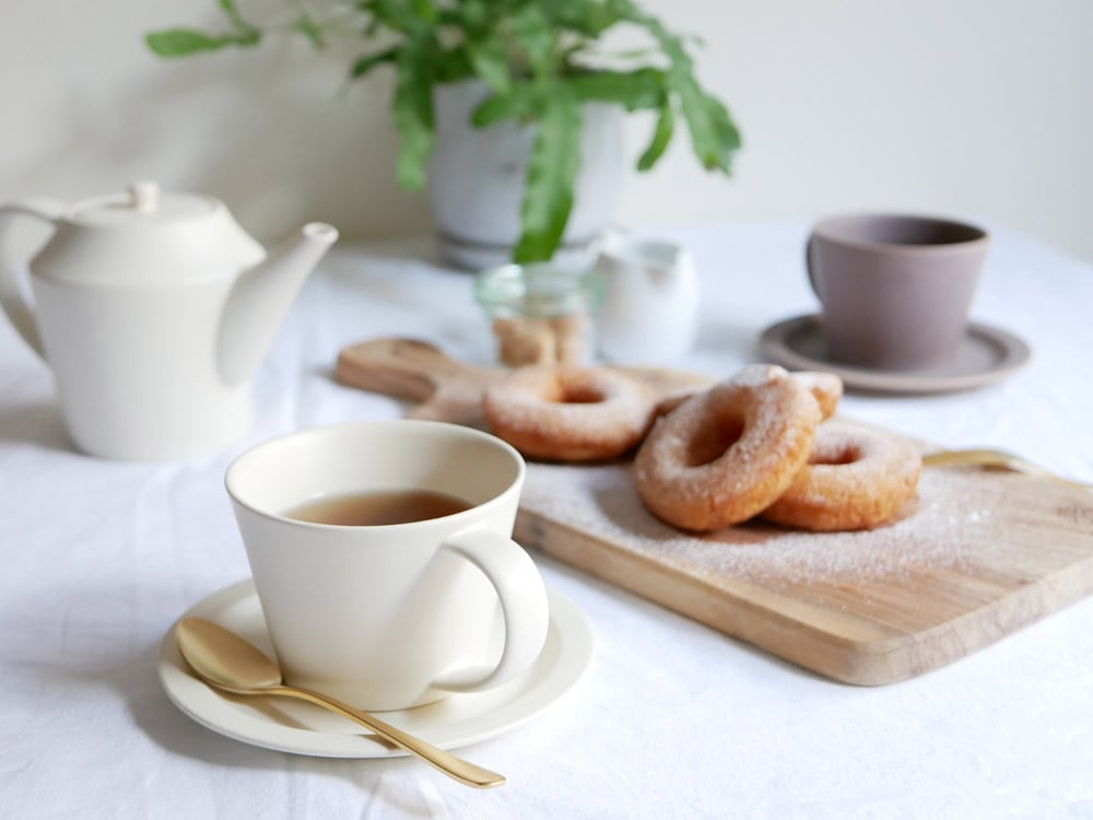 【SAKUZAN】Sara コーヒーカップとソーサーのギフトセット。クリーム色の磁器製カップとソーサーがテーブルに並べられています。