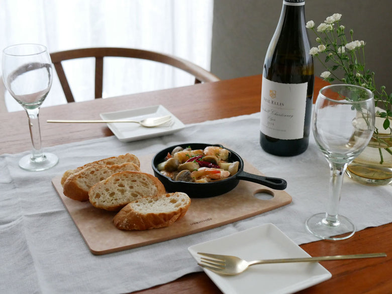 epicurean（エピキュリアン）のセルロース繊維製カッティングボードに食材や食器が配置されたテーブルの風景