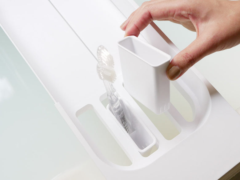 浴槽に設置された山崎のタワー伸縮バスタブトレー。飲み物や入浴用品を置けるABS樹脂製で、幅調整可能な実用的なデザイン