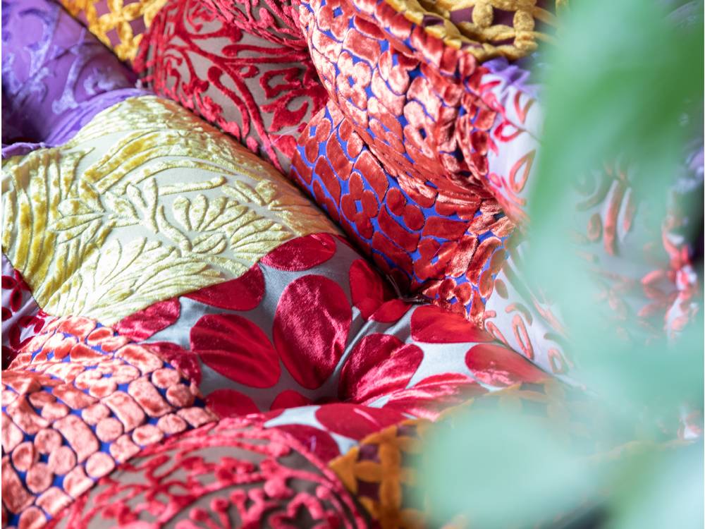 赤とピンクのパッチワーク柄クッションを備えたソファ