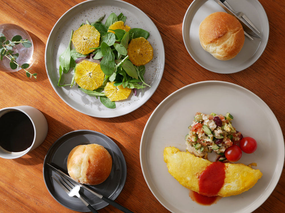 MOHEIM（モヘイム）製のせっ器プレートにフルーツと野菜が美しく盛り付けられ、テーブルに配置されている様子