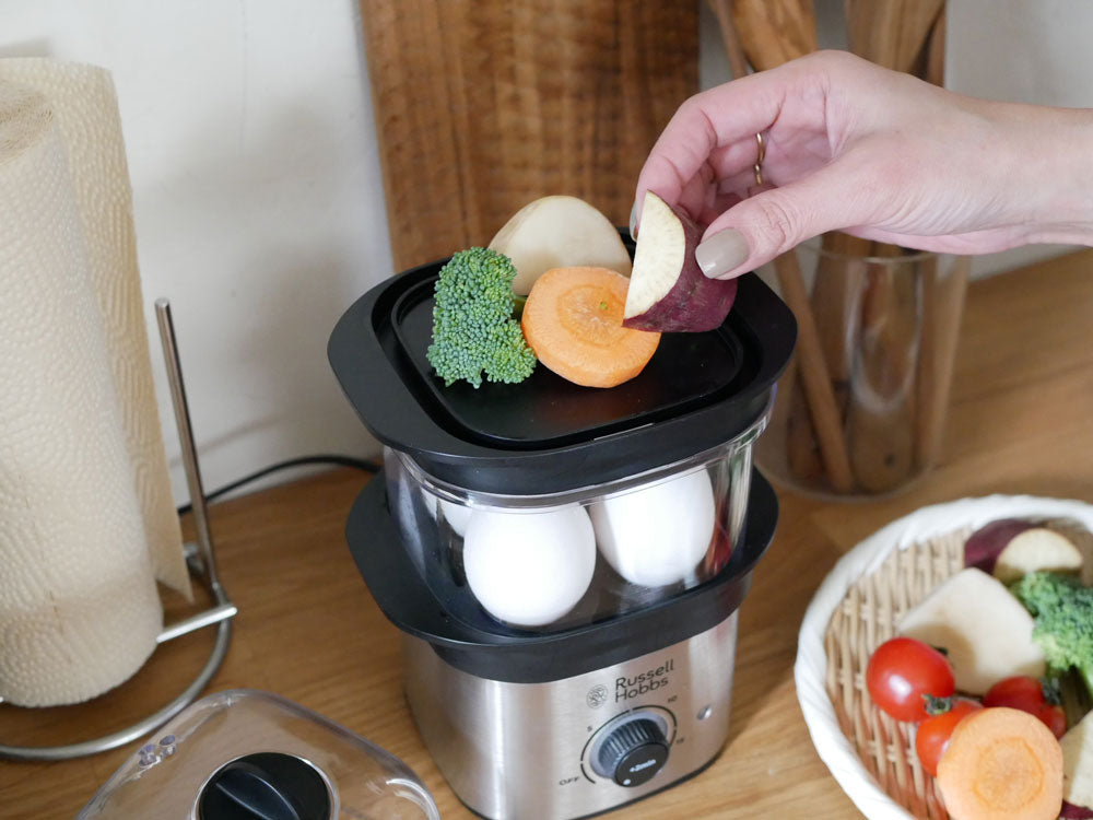 ラッセルホブスのクイックミニスチーマーと調理された野菜、食器がキッチンのテーブルに並べられている様子