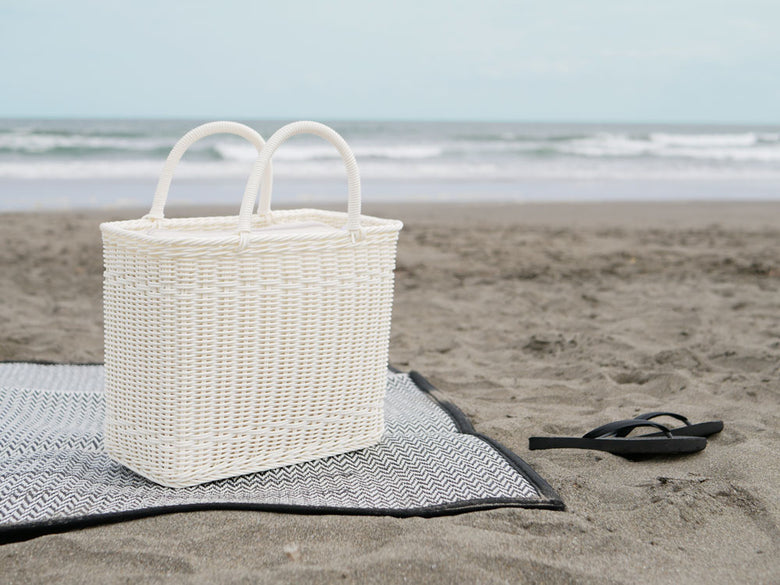 Creerクレエのユティル ピクニッククーラーバッグがビーチの砂浜に置かれ、波が打ち寄せる様子