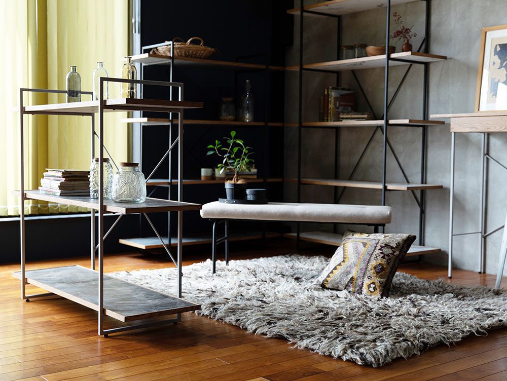 リビングルームに配置されたアデペシュのサムノルド クッションベンチ、木製シェルフ、ハードウッドフロア、観葉植物が調和するインテリア