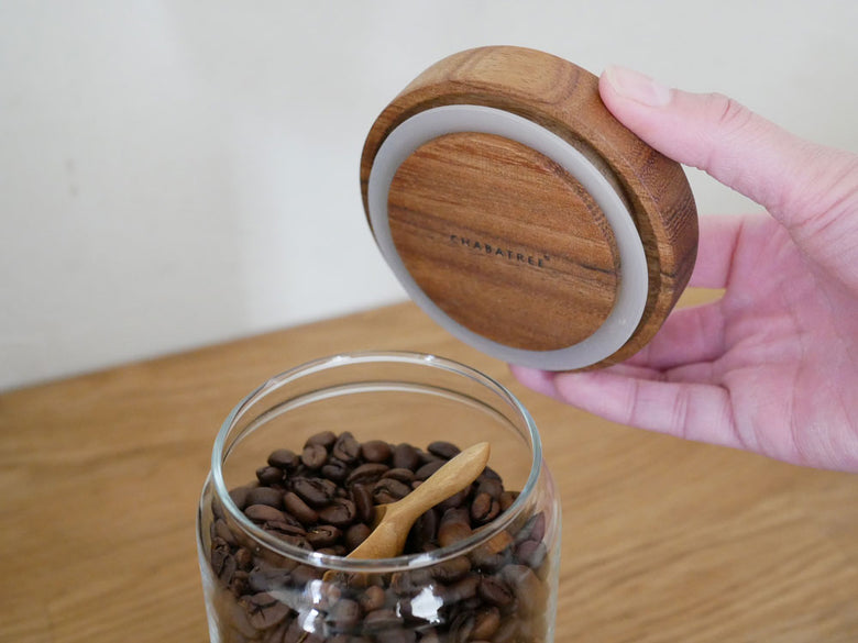 CHABATREEのサイノシュア ジャーとロータスティーサーバーが並んだ食品保存用セット。ソーダガラス製のジャーにはナッツや種子、ココア固形分が収納され、アカシア材の蓋と銅製の装飾が特徴的です。