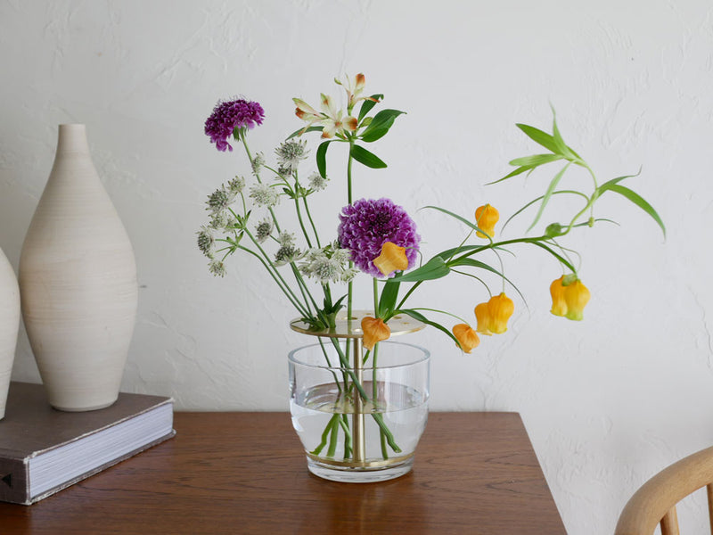フリッツ・ハンセンのIKEBANA、黄色い切花がガラスと真鍮の花瓶に生けられた生け花アレンジメント