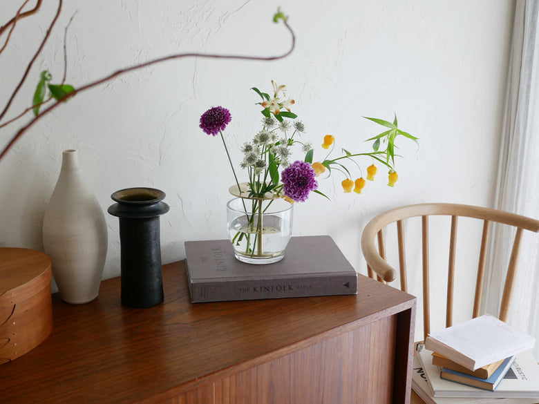 フリッツ・ハンセンのIKEBANAデザインによる真鍮とガラス製の花器に活けられた花束がテーブル上に配置されたインテリアシーン