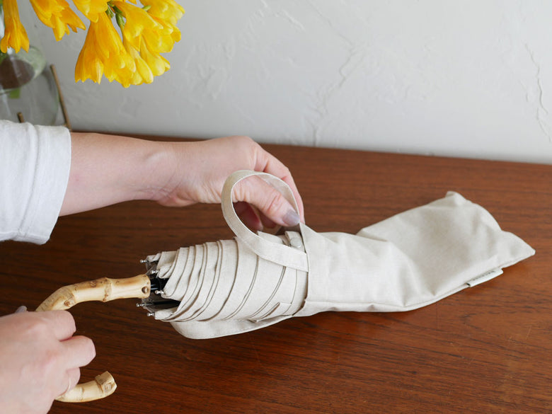 ビコーズのプレーンカラー長傘が鋏、ロープ、リネンと一緒に展示されている画像。